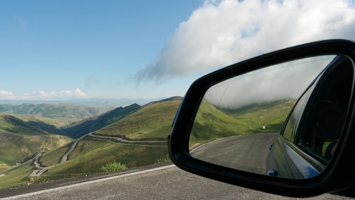 Imagem de um retrovisor de carro com uma bela paisagem de estrada na luz do dia