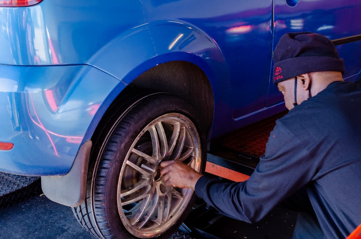 Imagem de um homem trocando o pneu de um carro azul